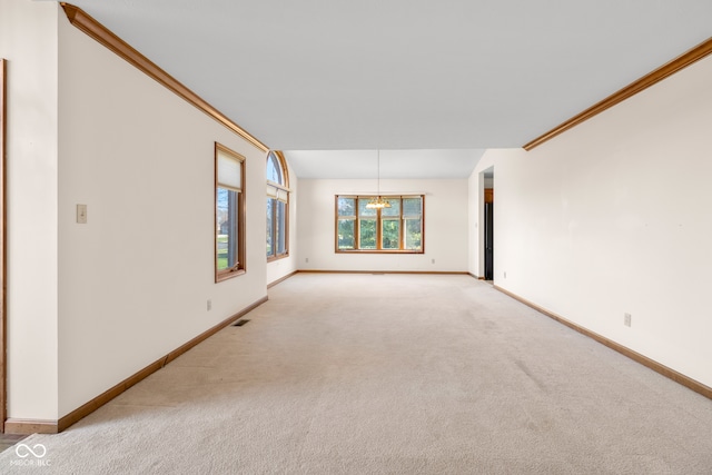 carpeted spare room featuring ornamental molding and an inviting chandelier