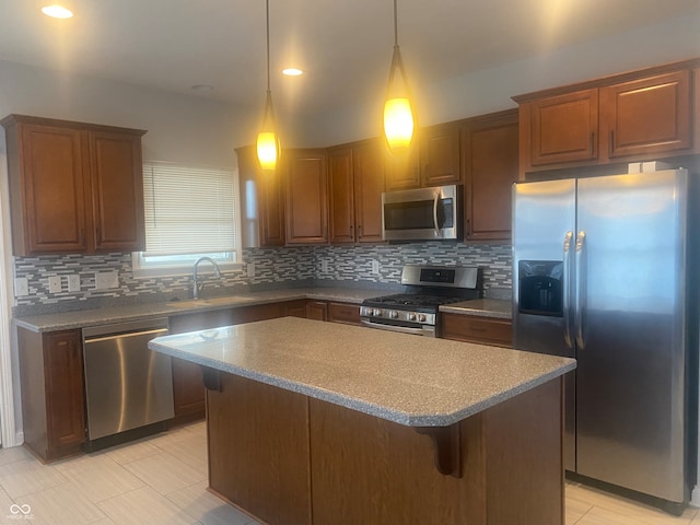 kitchen featuring sink, hanging light fixtures, decorative backsplash, a kitchen island, and appliances with stainless steel finishes