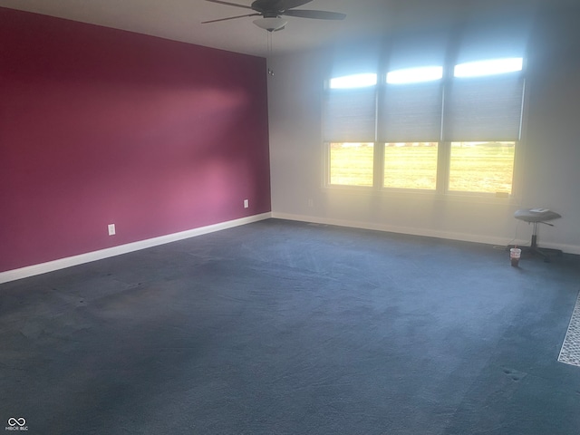 unfurnished room featuring ceiling fan and dark colored carpet