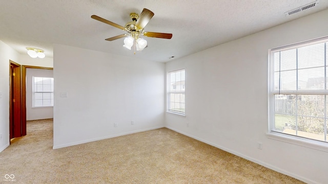 spare room featuring ceiling fan, light colored carpet, and a textured ceiling