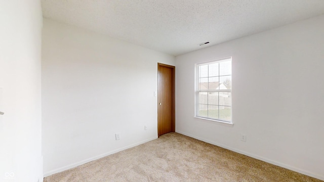 carpeted empty room featuring a textured ceiling