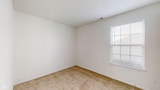 unfurnished room featuring a textured ceiling and light carpet