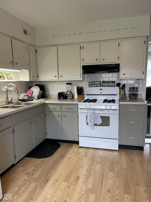 kitchen with decorative backsplash, light hardwood / wood-style floors, sink, and gas range gas stove