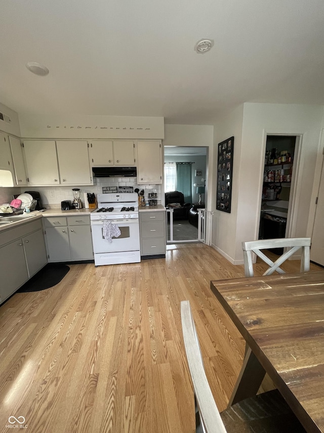 kitchen featuring gray cabinets, backsplash, white range with gas cooktop, and light hardwood / wood-style flooring