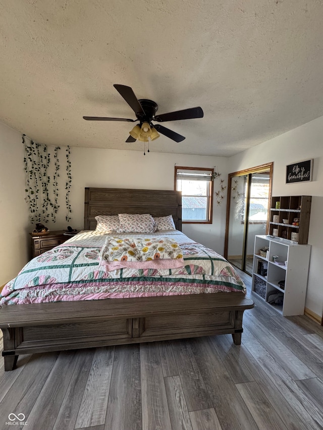 bedroom featuring ceiling fan, wood-type flooring, and a textured ceiling