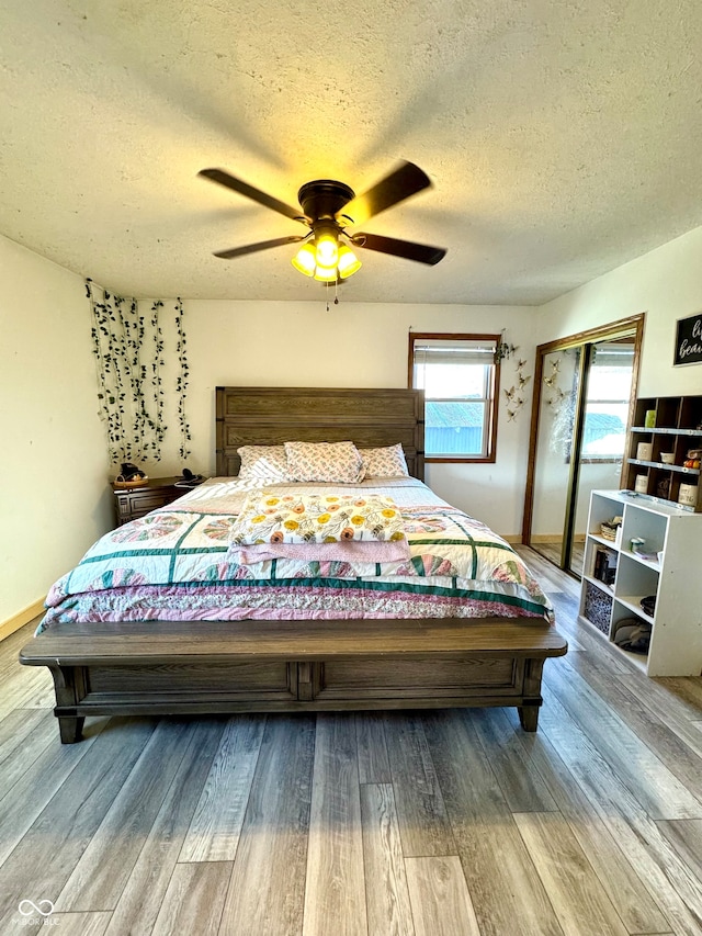 bedroom with ceiling fan, light wood-type flooring, and a textured ceiling