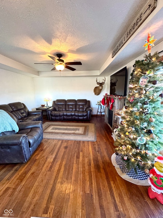 living room featuring ceiling fan, dark hardwood / wood-style floors, and a textured ceiling