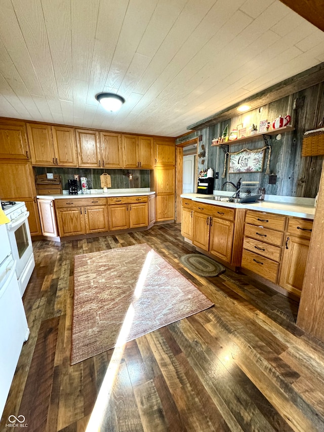 kitchen with wooden walls, white range, dark hardwood / wood-style floors, and sink