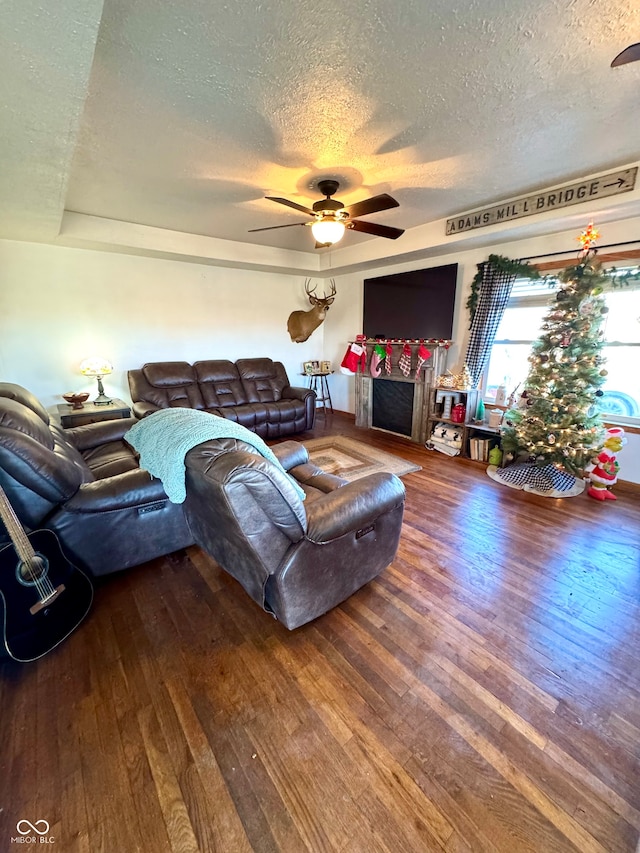 living room with hardwood / wood-style flooring, ceiling fan, and a textured ceiling