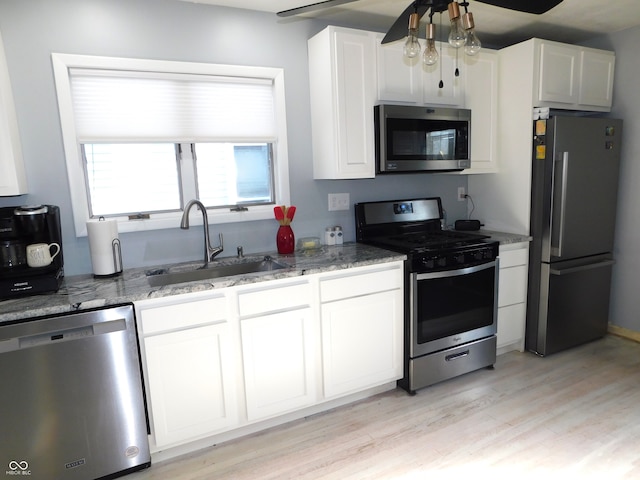 kitchen with white cabinets, appliances with stainless steel finishes, dark stone counters, and sink