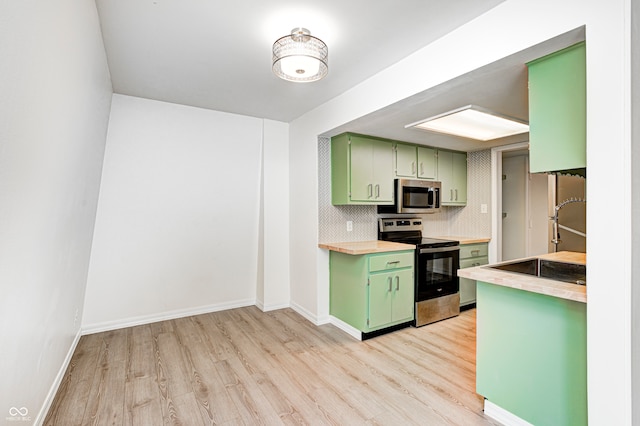 kitchen with green cabinets, light wood-type flooring, and appliances with stainless steel finishes