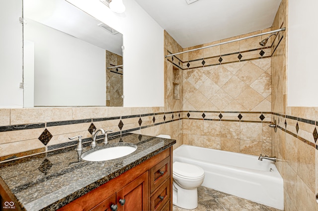 full bathroom with vanity, toilet, tile walls, and tiled shower / bath