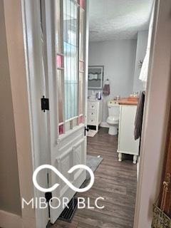 bathroom with hardwood / wood-style floors, a textured ceiling, and toilet