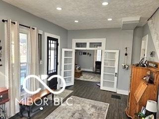 interior space featuring a textured ceiling, dark wood-type flooring, and french doors