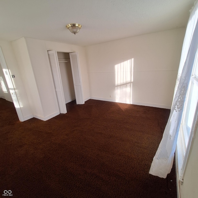 unfurnished bedroom with dark colored carpet and a closet