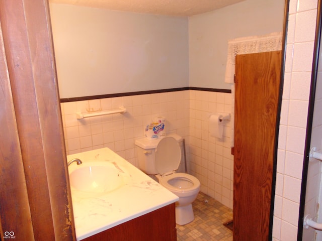 bathroom featuring vanity, tile patterned flooring, toilet, a textured ceiling, and tile walls