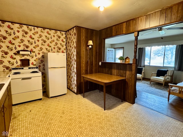 kitchen with wood walls, ceiling fan, light hardwood / wood-style floors, and white appliances