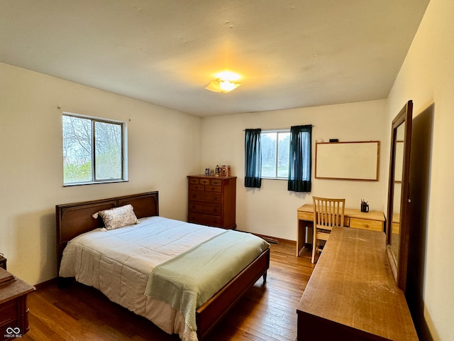 bedroom with dark wood-type flooring and multiple windows