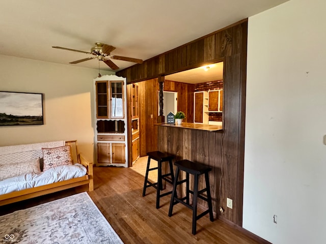 living room featuring ceiling fan, wood walls, and dark wood-type flooring