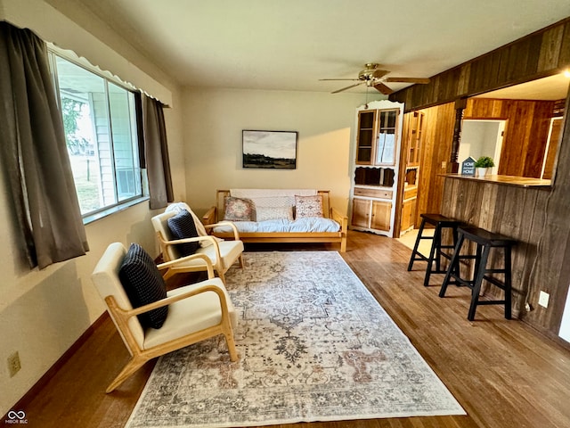 living room featuring hardwood / wood-style floors, ceiling fan, and wood walls