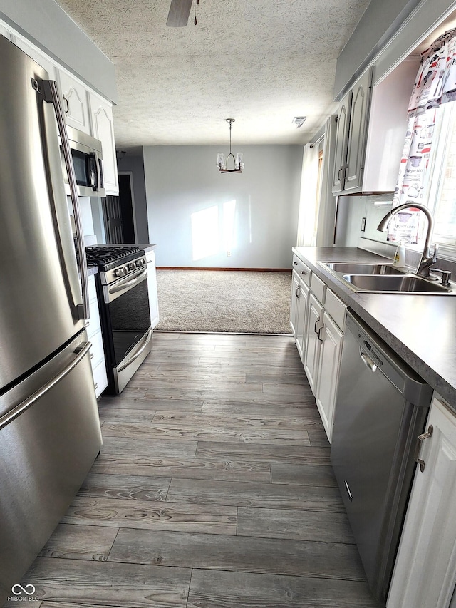 kitchen featuring white cabinetry, sink, pendant lighting, and stainless steel appliances