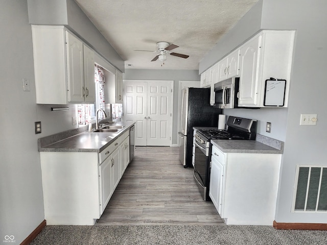 kitchen featuring white cabinetry, sink, stainless steel appliances, and ceiling fan