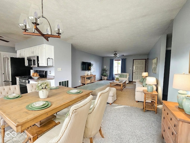 carpeted dining space with ceiling fan with notable chandelier and a textured ceiling