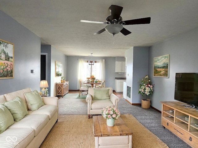 living room featuring ceiling fan, light colored carpet, and a textured ceiling