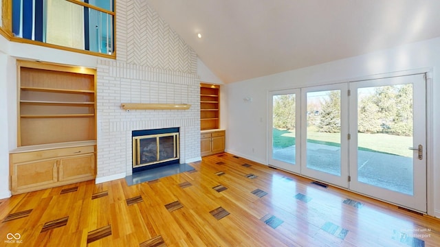 unfurnished living room with a fireplace, built in features, high vaulted ceiling, and hardwood / wood-style flooring