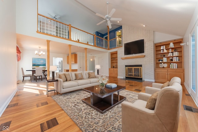 living room featuring a brick fireplace, ceiling fan with notable chandelier, high vaulted ceiling, and a healthy amount of sunlight