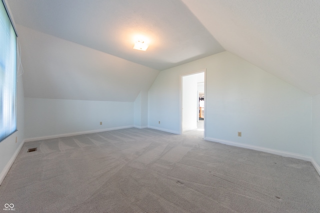 additional living space with light carpet and lofted ceiling