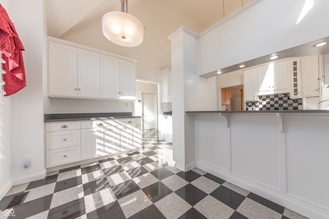 kitchen featuring decorative light fixtures, white cabinetry, and a towering ceiling