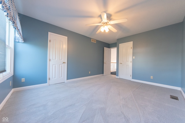 unfurnished bedroom featuring ceiling fan, light carpet, and multiple windows