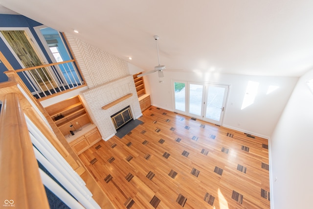 unfurnished living room featuring ceiling fan, french doors, wood-type flooring, and a brick fireplace