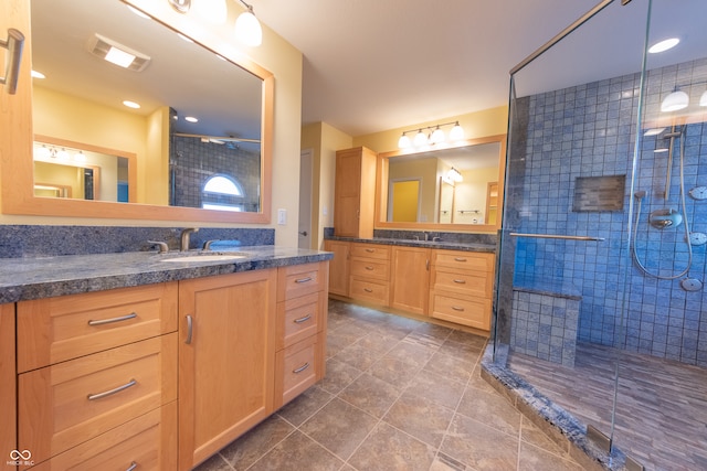 bathroom featuring tile patterned flooring, vanity, and tiled shower