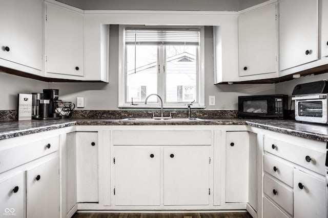 kitchen with white cabinets, sink, and dark wood-type flooring