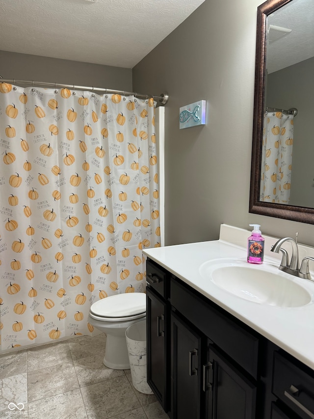 bathroom featuring a textured ceiling, toilet, and vanity