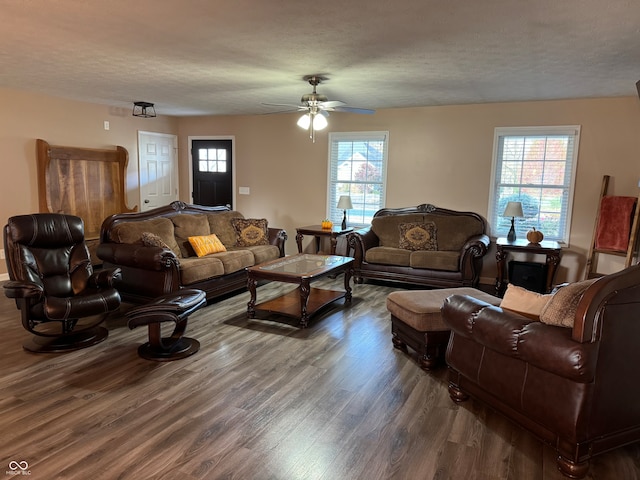 living room with a textured ceiling, ceiling fan, dark hardwood / wood-style flooring, and plenty of natural light