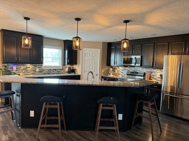 kitchen with a kitchen breakfast bar, pendant lighting, and stainless steel appliances