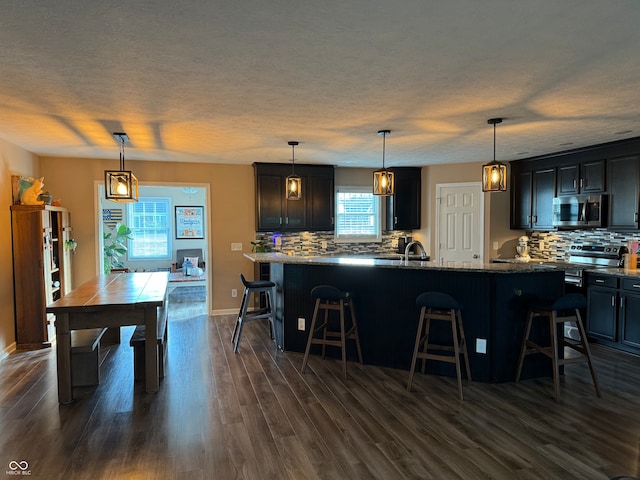 kitchen with a kitchen island, decorative light fixtures, stone countertops, dark hardwood / wood-style floors, and a breakfast bar