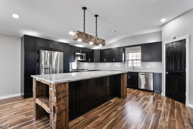 kitchen featuring pendant lighting, a center island, lofted ceiling, dark wood-type flooring, and appliances with stainless steel finishes