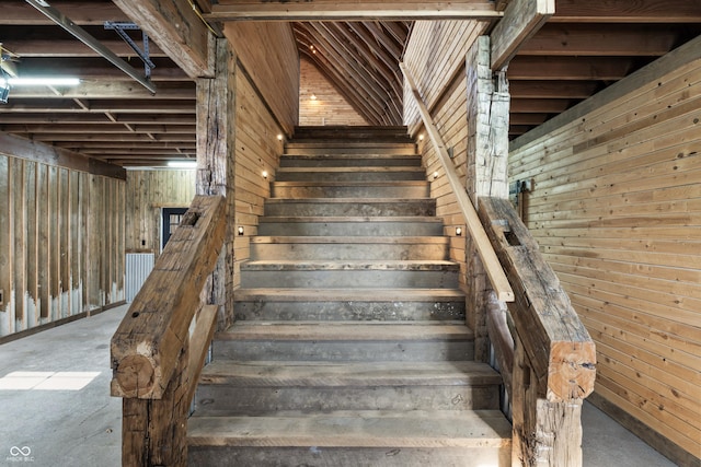 staircase with wooden walls and concrete flooring