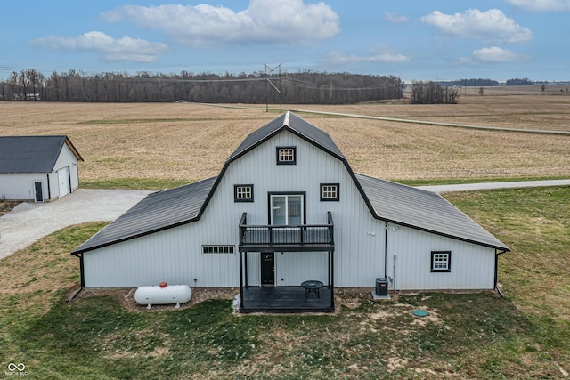 rear view of property featuring a yard, cooling unit, a rural view, and an outdoor structure