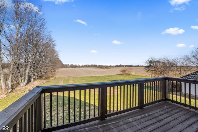 wooden deck with a rural view and a lawn