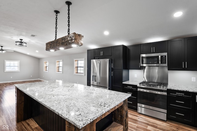 kitchen featuring a center island, hanging light fixtures, stainless steel appliances, light hardwood / wood-style flooring, and lofted ceiling