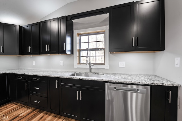 kitchen featuring light stone countertops, sink, stainless steel dishwasher, vaulted ceiling, and light wood-type flooring