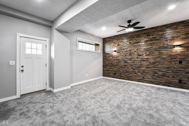 entrance foyer featuring a textured ceiling, ceiling fan, carpet floors, and wood walls