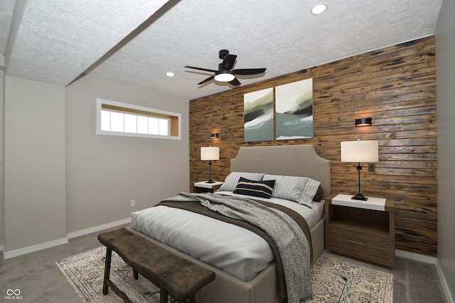 bedroom featuring carpet, a textured ceiling, ceiling fan, and wood walls