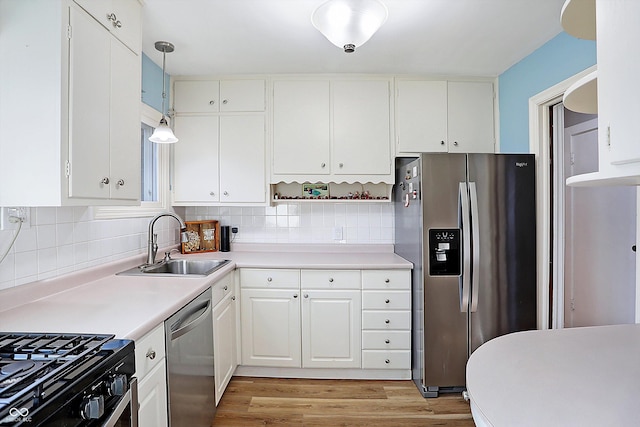 kitchen featuring white cabinetry, sink, light hardwood / wood-style floors, pendant lighting, and appliances with stainless steel finishes