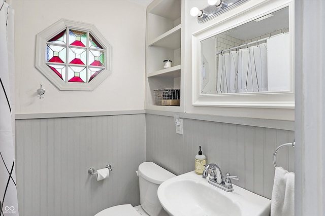 bathroom featuring built in shelves, toilet, and sink